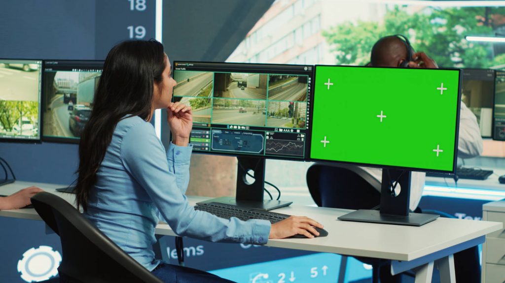 woman working with surveillance footage and green screen on computer